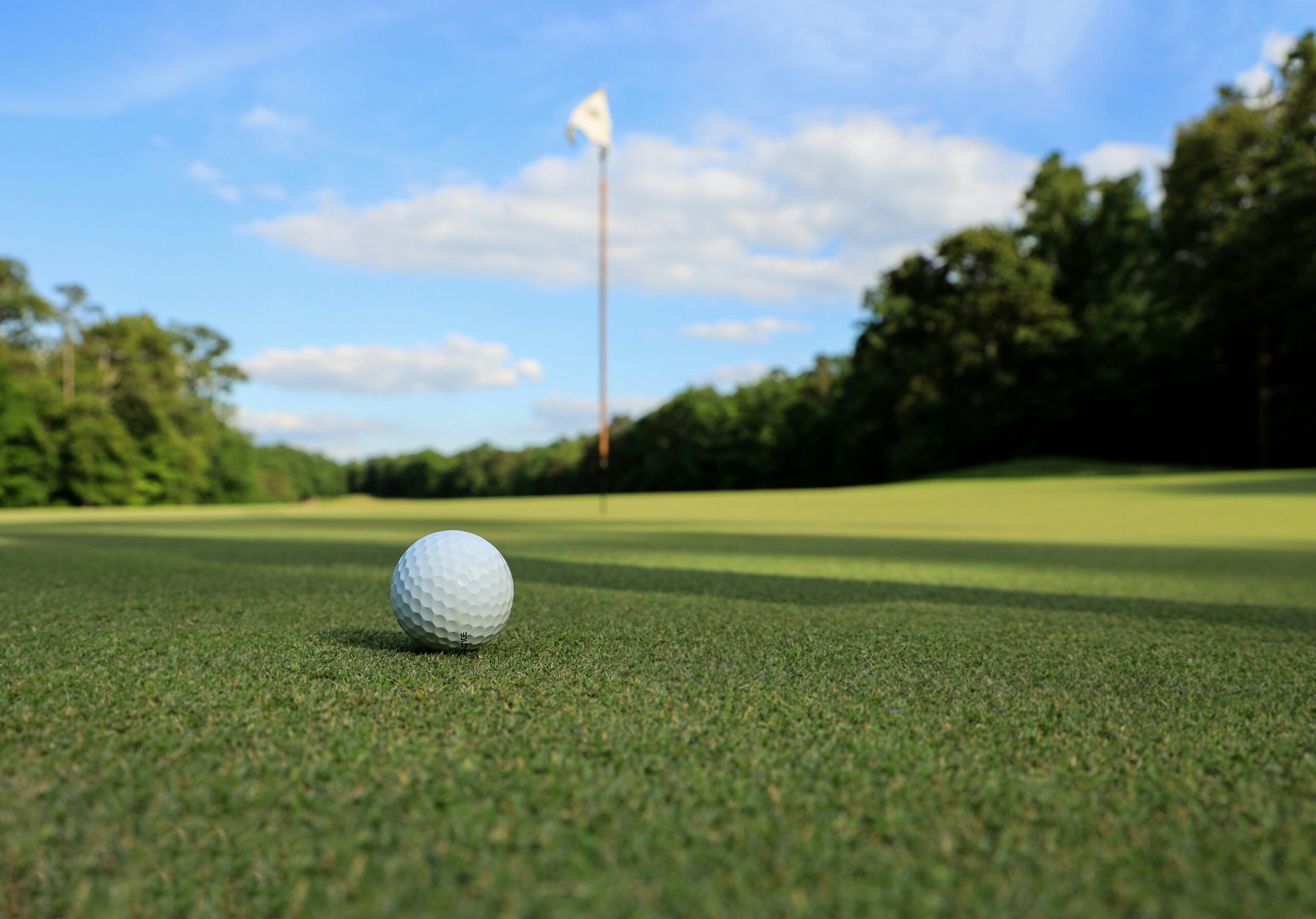 Golf ball on green with flag in background